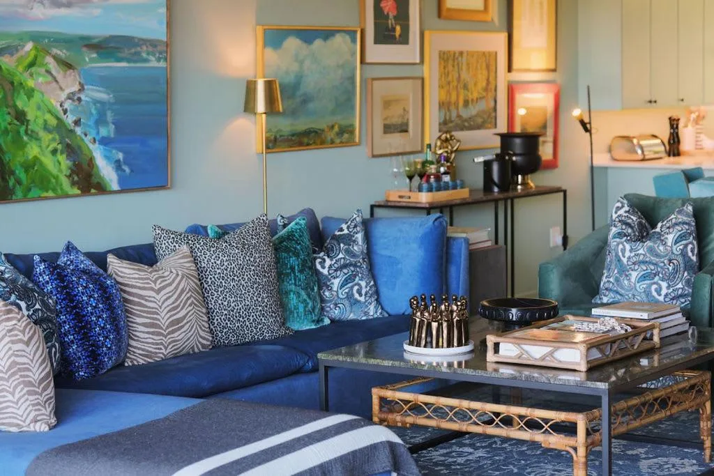 Coastal-themed lounge with blue sofa, patterned pillows, and gallery wall artwork