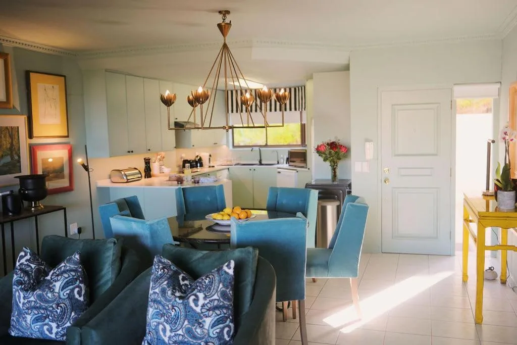 Open-plan lounge and dining area with blue upholstered chairs and modern pendant lighting