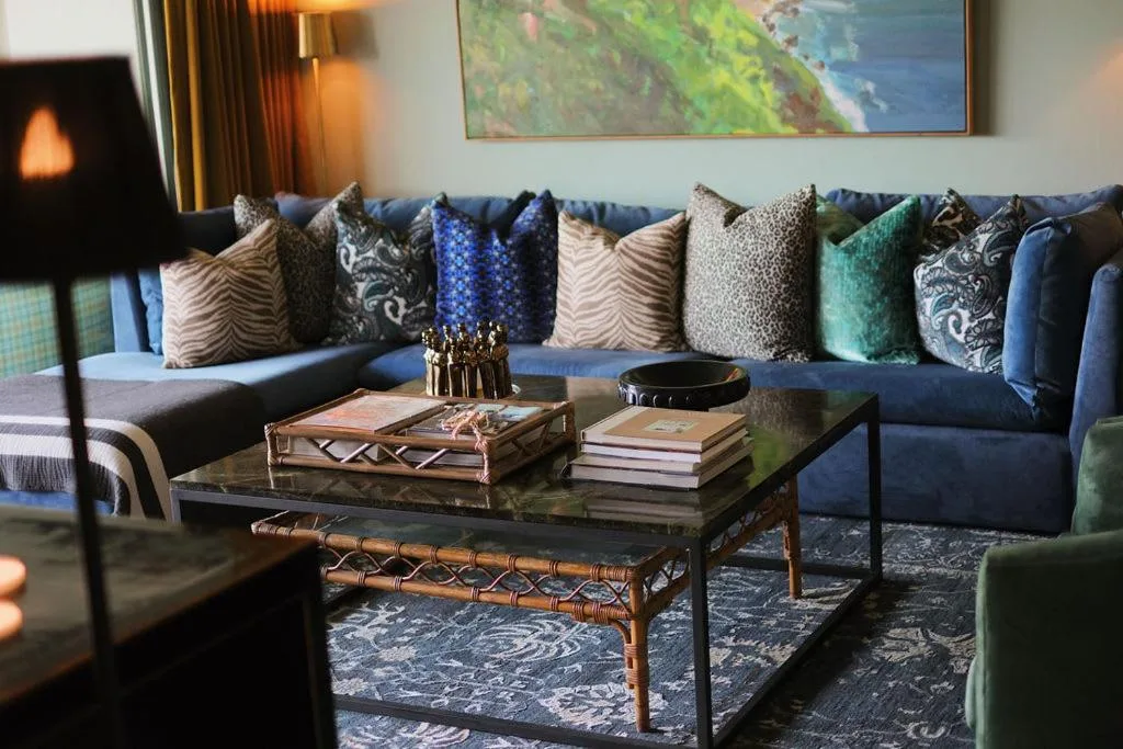 Luxurious lounge with blue sofa, decorative pillows, and coastal artwork