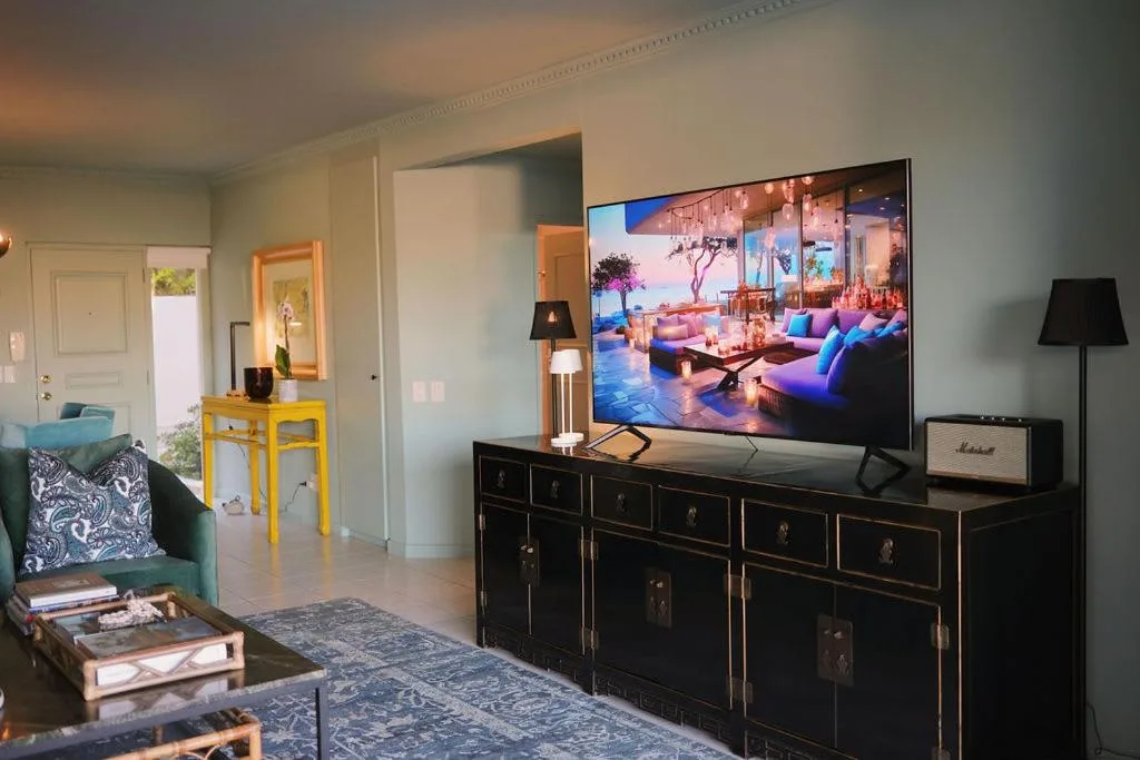 Modern lounge with black media console, flat-screen TV, and patterned armchair