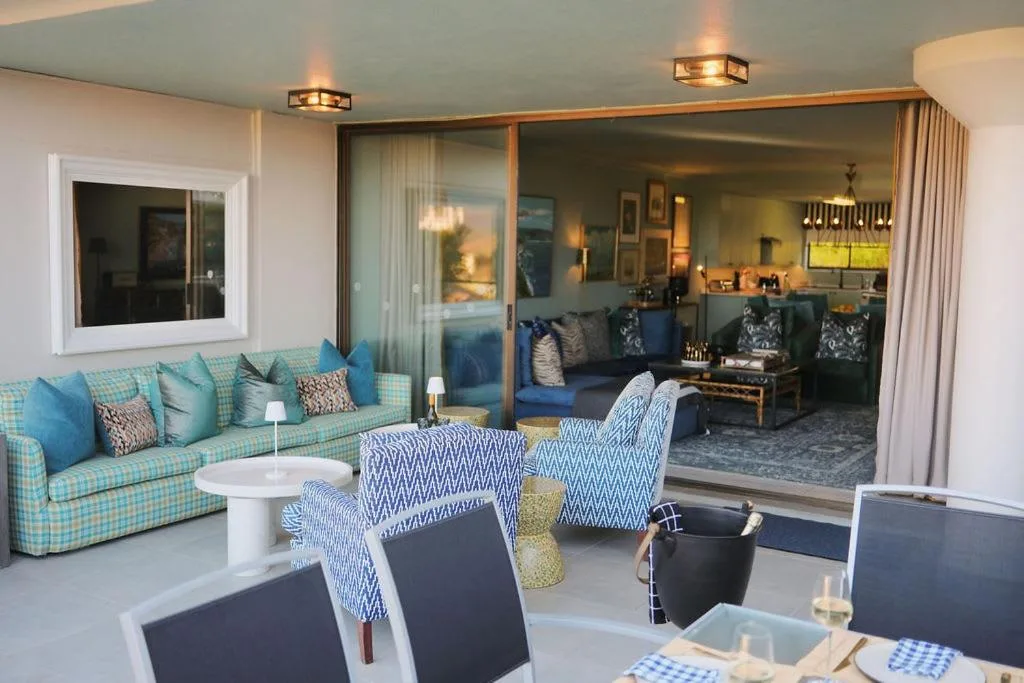 Bright open-plan lounge with turquoise seating and contemporary furnishings overlooking deck