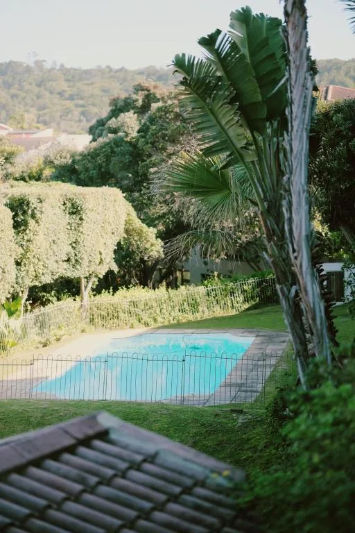 Turquoise swimming pool nestled in manicured gardens with mountain views beyond