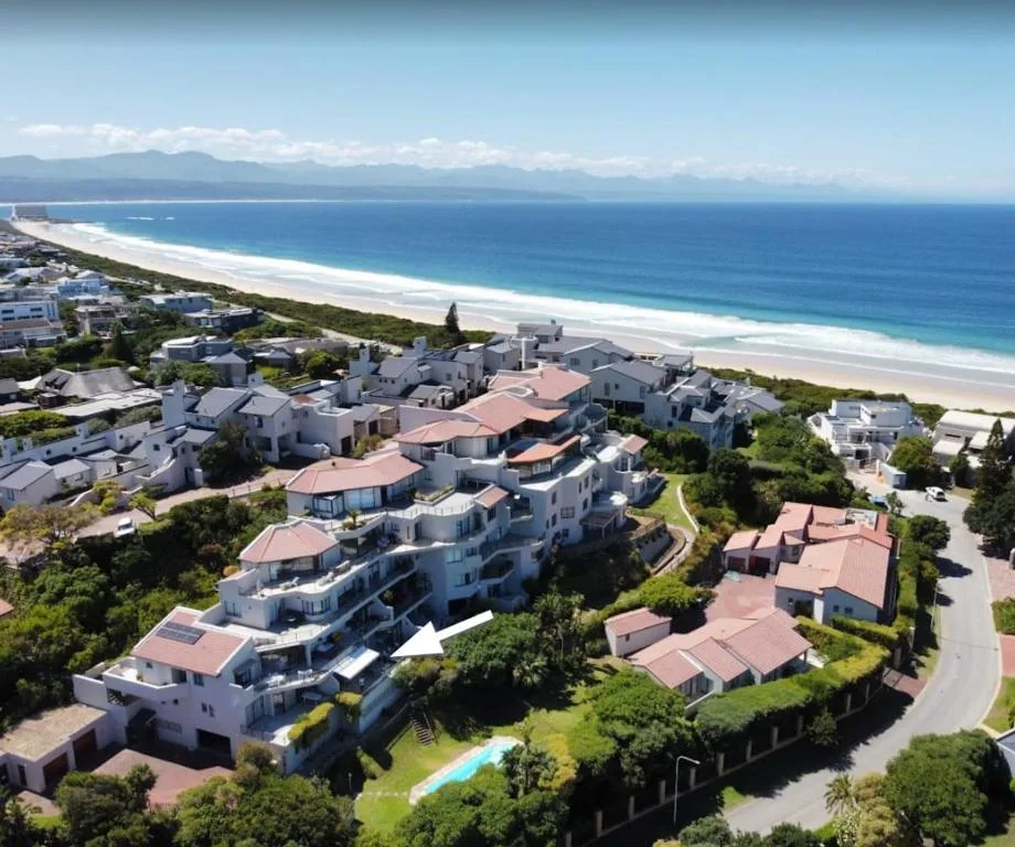 Aerial view of beachfront property with pristine white sand and mountains beyond