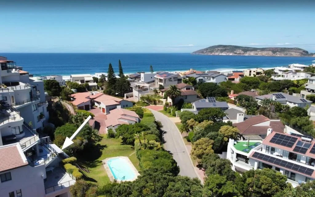 Aerial view of coastal town with beach, ocean, and island in distance