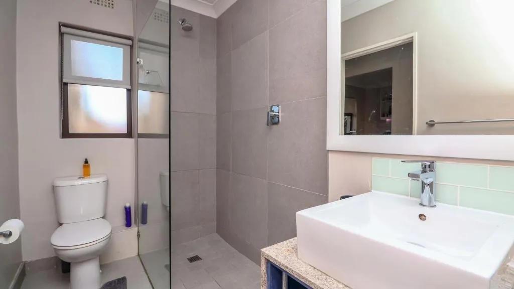Modern bathroom with toilet, vanity sink, and walk-in shower enclosure