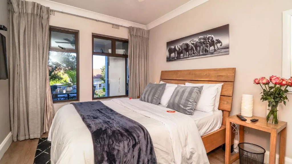 Bright bedroom with wooden bed frame and striped cushions, fresh flowers on nightstand