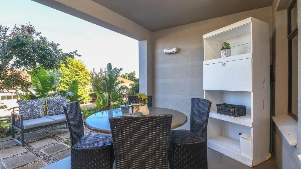Covered patio with round dining table and garden views