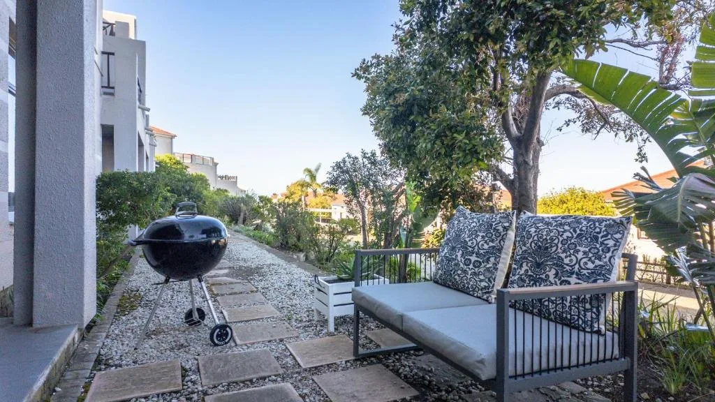 Outdoor seating area with braai grill and garden views in afternoon sunlight