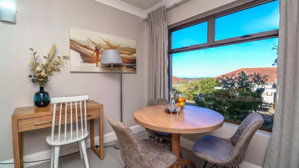 Modern dining area with round wooden table and scenic mountain view through large windows