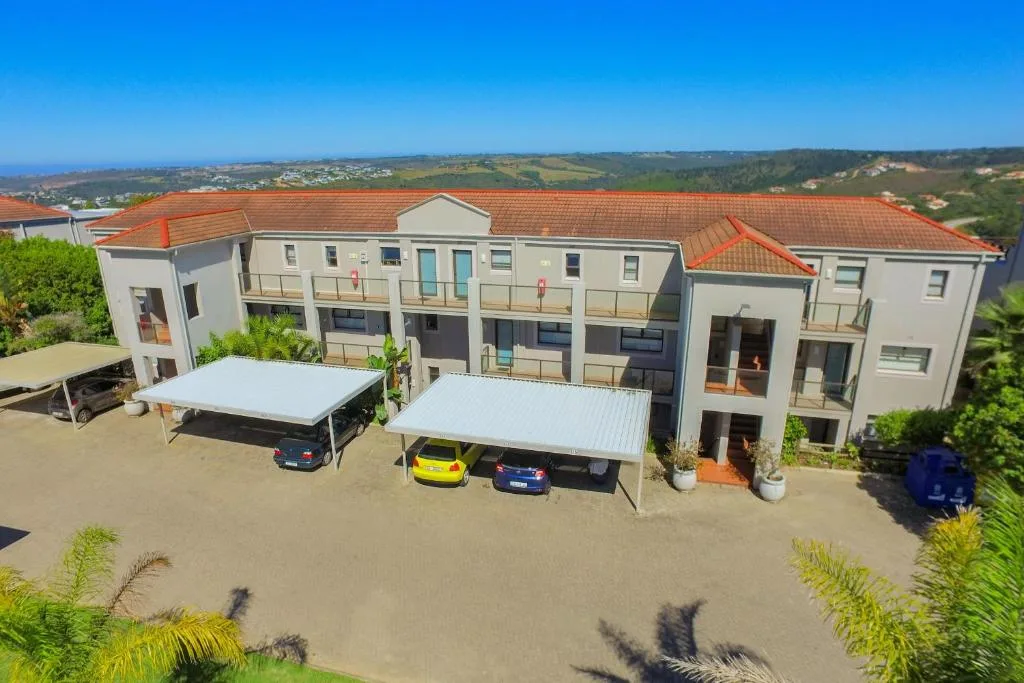 Modern multi-unit apartment building with terracotta roof and coastal views