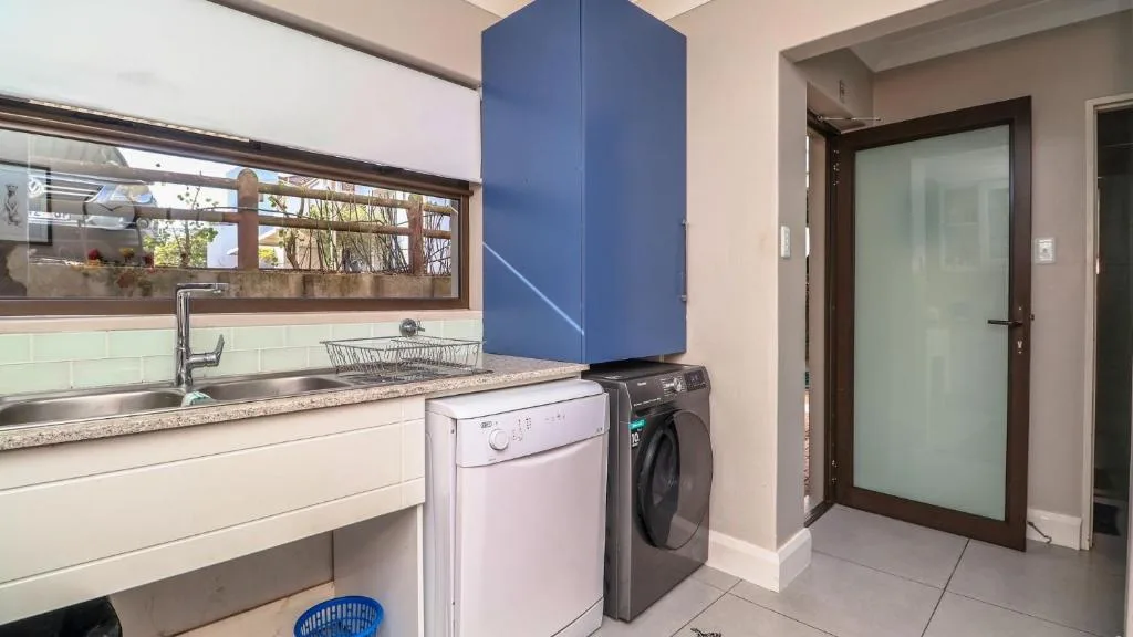 Modern kitchen with sink, washing machine, dryer, and blue storage cabinet