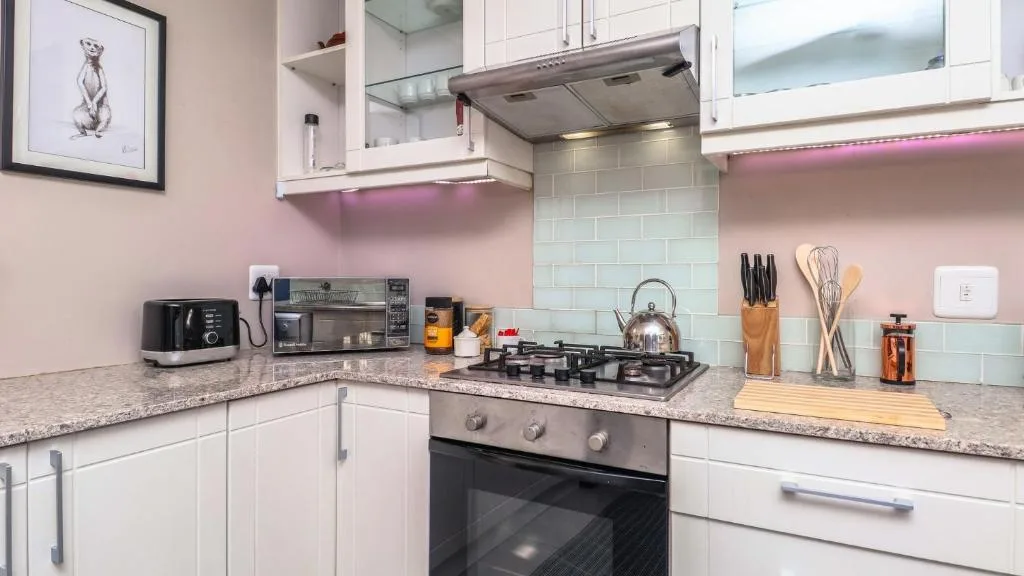 Modern kitchen with white cabinetry, gas stove, granite countertops, and mint subway tile backsplash