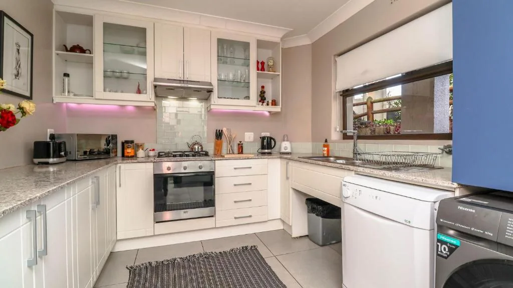 Modern cream kitchen with gas stove, white cabinetry, granite counters, and appliances