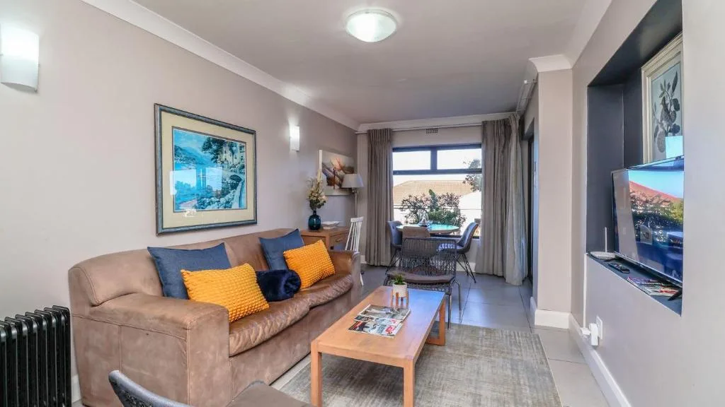 Spacious living room with beige sofa, blue and orange cushions, wooden coffee table