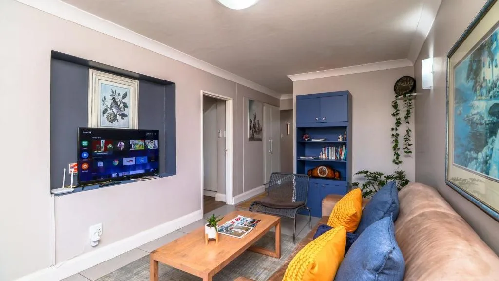 Modern lounge with wall-mounted TV, comfortable sofa, and blue storage shelving