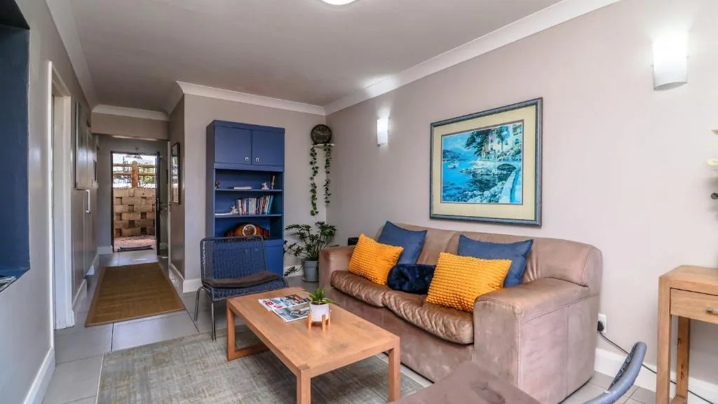 Living room with beige sofa, blue shelving, and framed coastal artwork