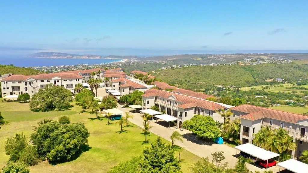 Coastal valley vista with lush green hills, ocean, and distant beach town