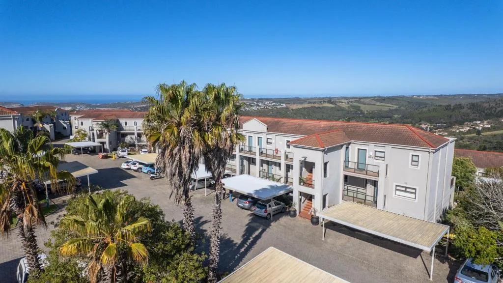 Aerial view of modern white apartment building with ocean and mountains visible beyond
