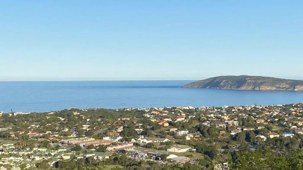 Coastal panorama showing Plettenberg Bay, green hillside town, and distant headland