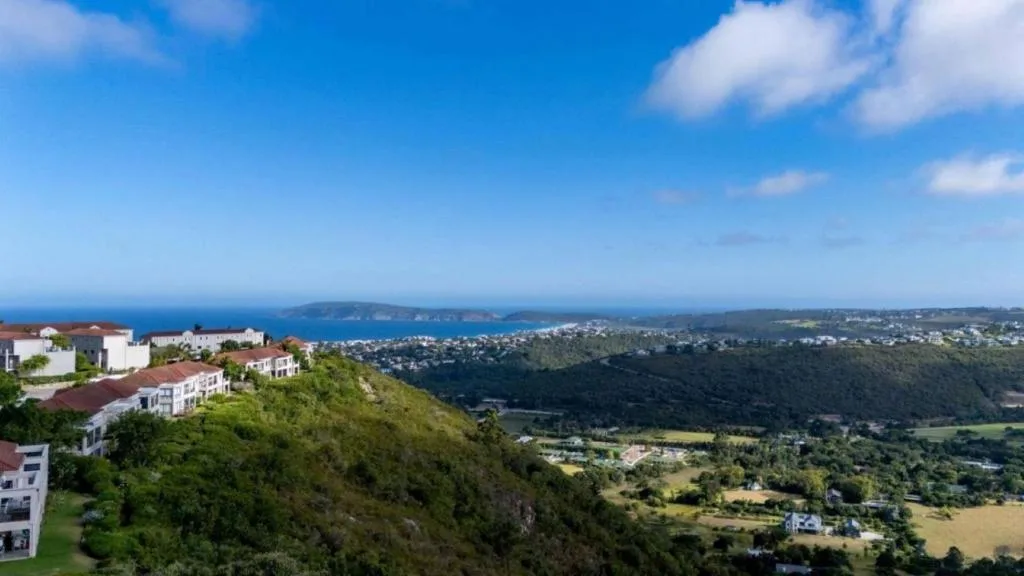 Panoramic coastal landscape with blue ocean, forested valleys, and seaside town