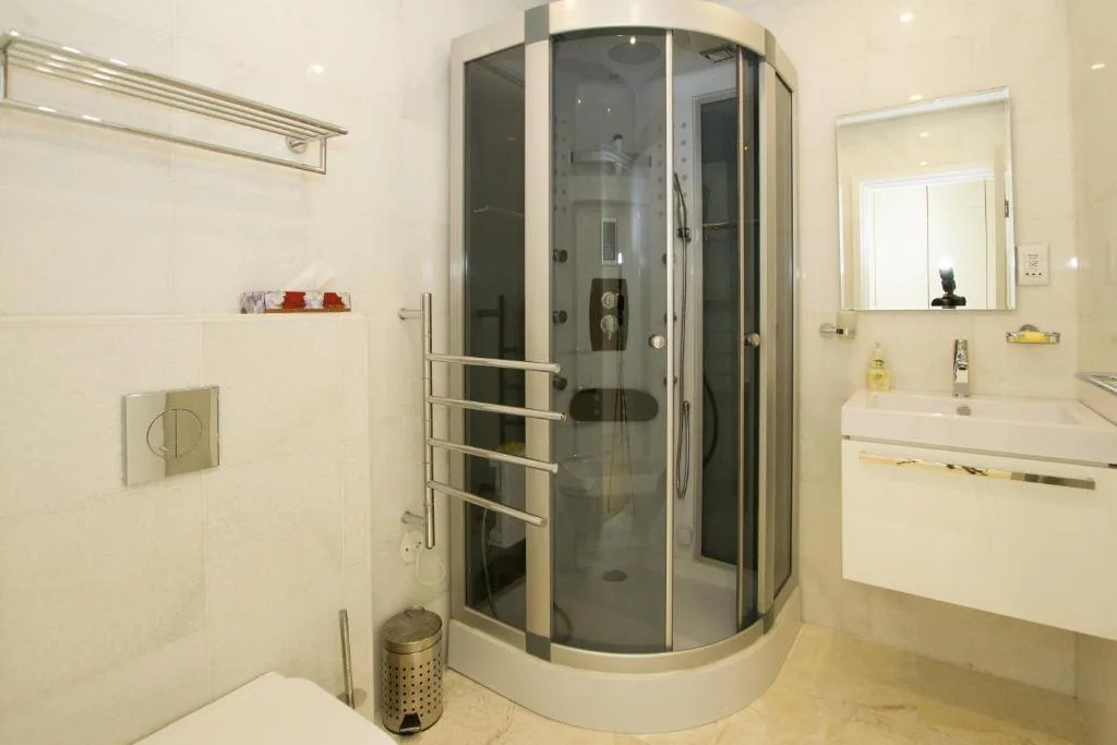 Modern bathroom with curved glass shower cubicle and white vanity sink