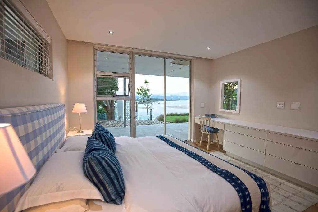 Modern bedroom with water views through large sliding glass doors