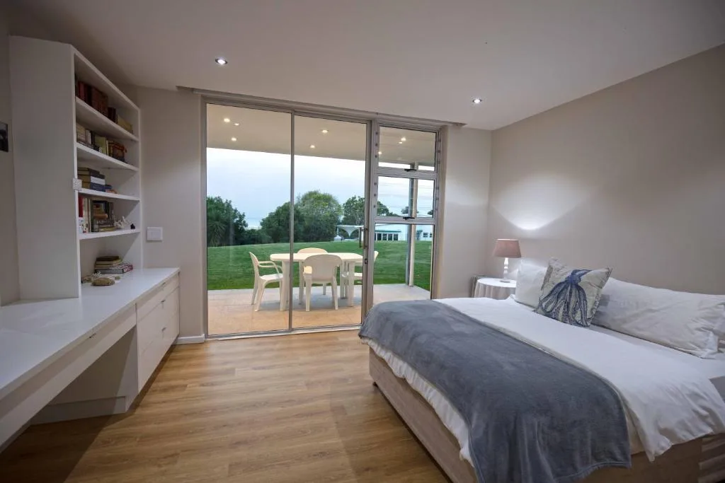 Spacious bedroom with bed, desk, and sliding glass doors to garden view