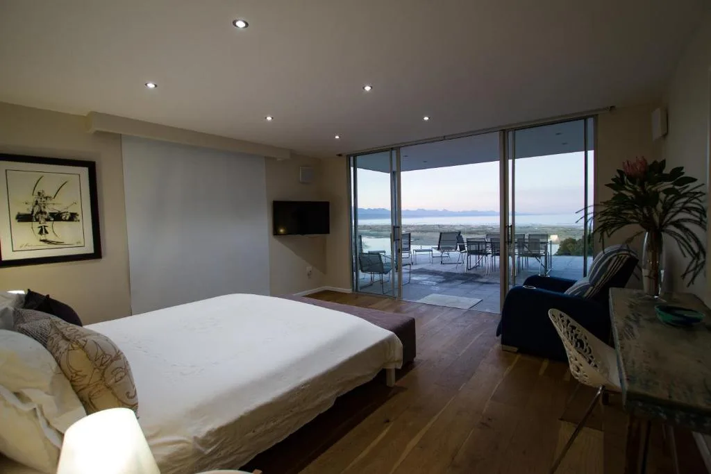 Spacious bedroom with panoramic windows overlooking coastal lagoon views