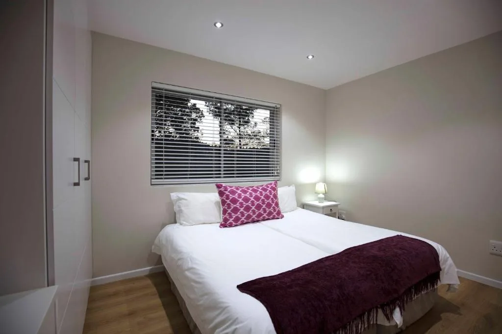 Modern bedroom with queen bed, burgundy accents, and venetian blind window