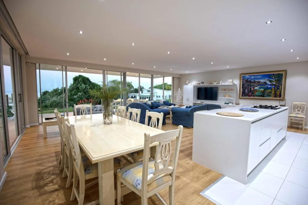 Open-plan dining area with wooden table and cream chairs overlooking the Garden Route