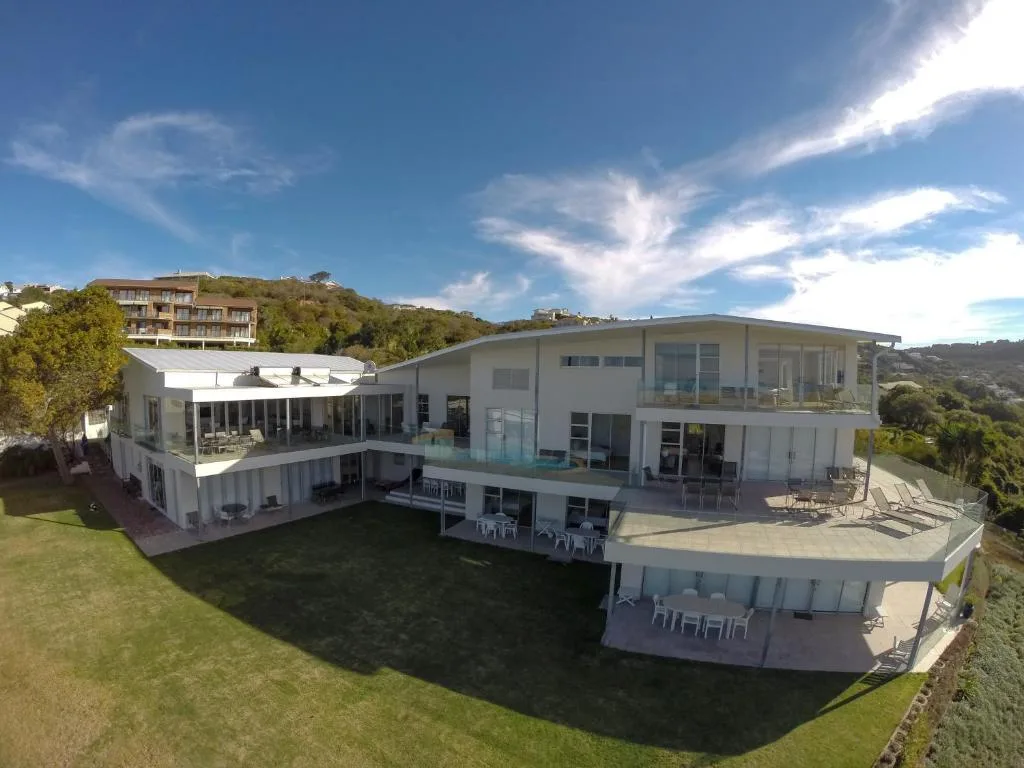 Modern multi-level white home with wraparound decks overlooking manicured gardens
