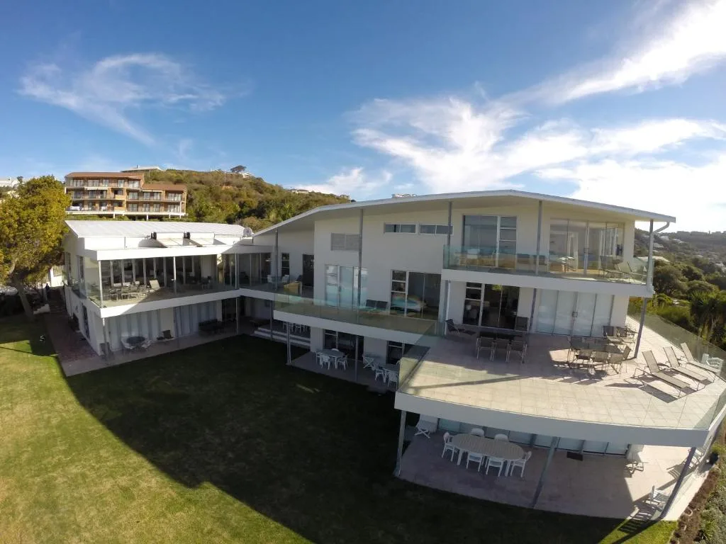 Modern white multi-level house with expansive decks overlooking manicured gardens