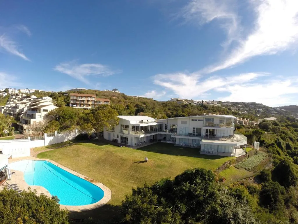 Modern white house with pool and manicured lawn overlooking valley
