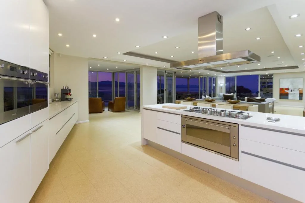 Modern open-plan kitchen with white cabinetry, stainless steel appliances, and panoramic evening views
