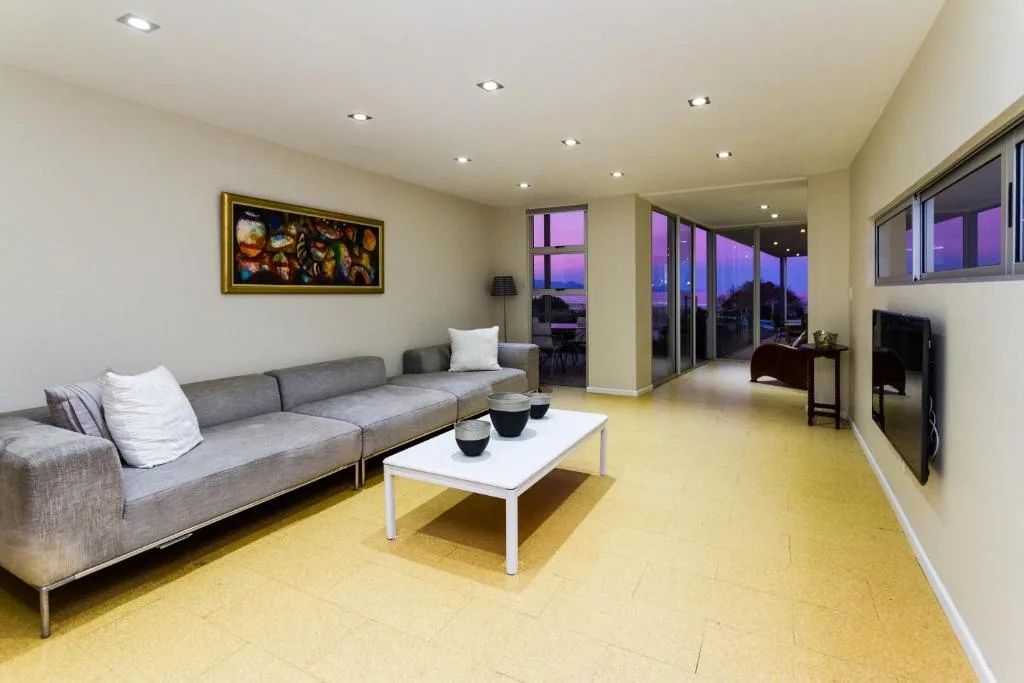 Modern lounge with gray sofa, white coffee table, and panoramic windows at dusk