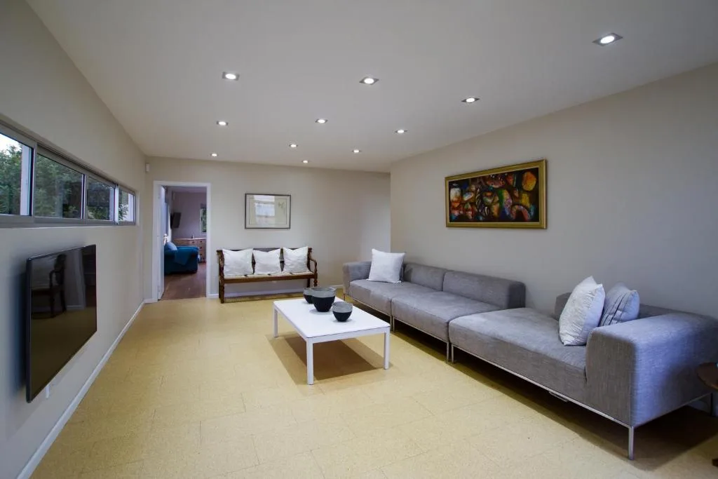 Modern lounge with gray sofa, TV, and artwork on cream walls