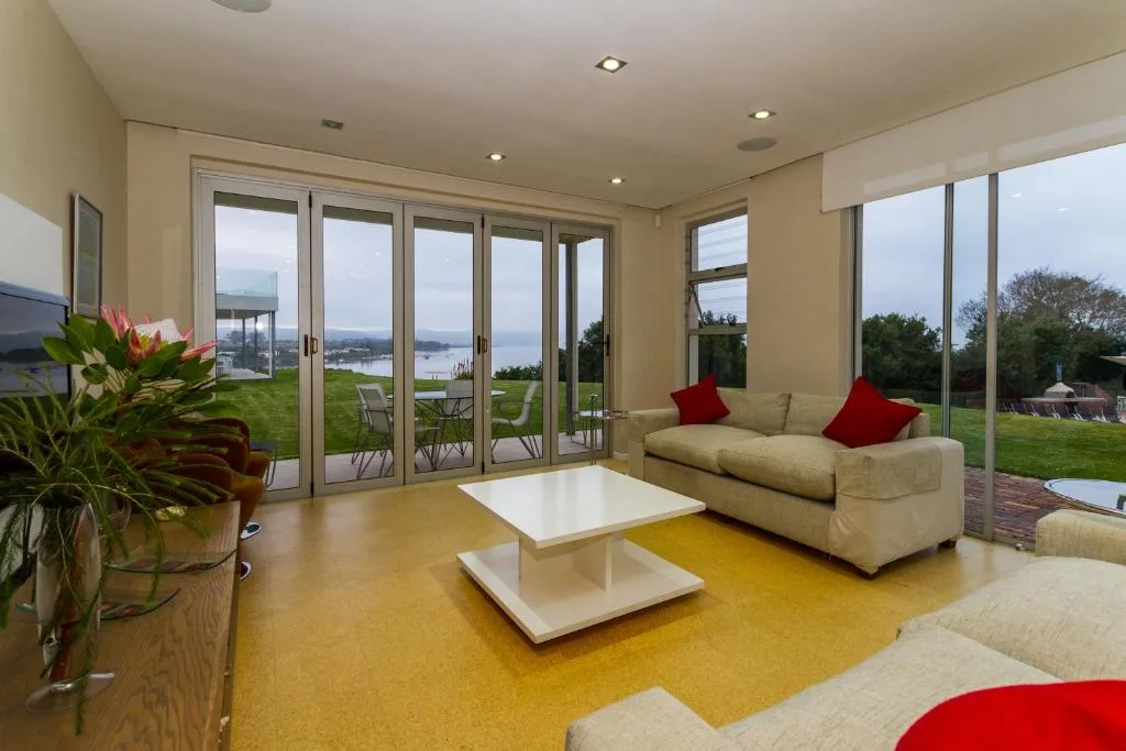 Modern lounge with cream sofas, red cushions, lagoon views through glass doors