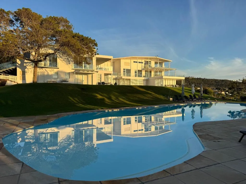 Curved swimming pool with building and manicured lawn reflection