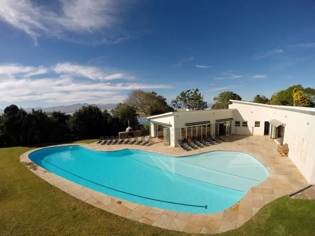 Blue kidney-shaped swimming pool with loungers and mountain views beyond