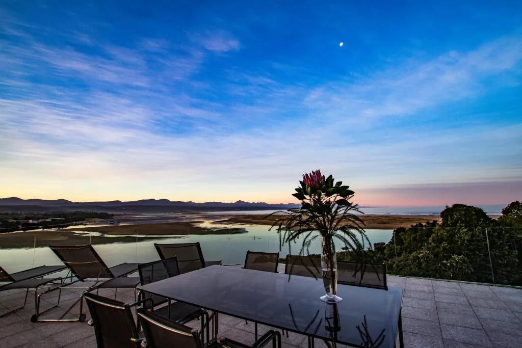 Sunset view over lagoon and mountains from elevated deck with loungers