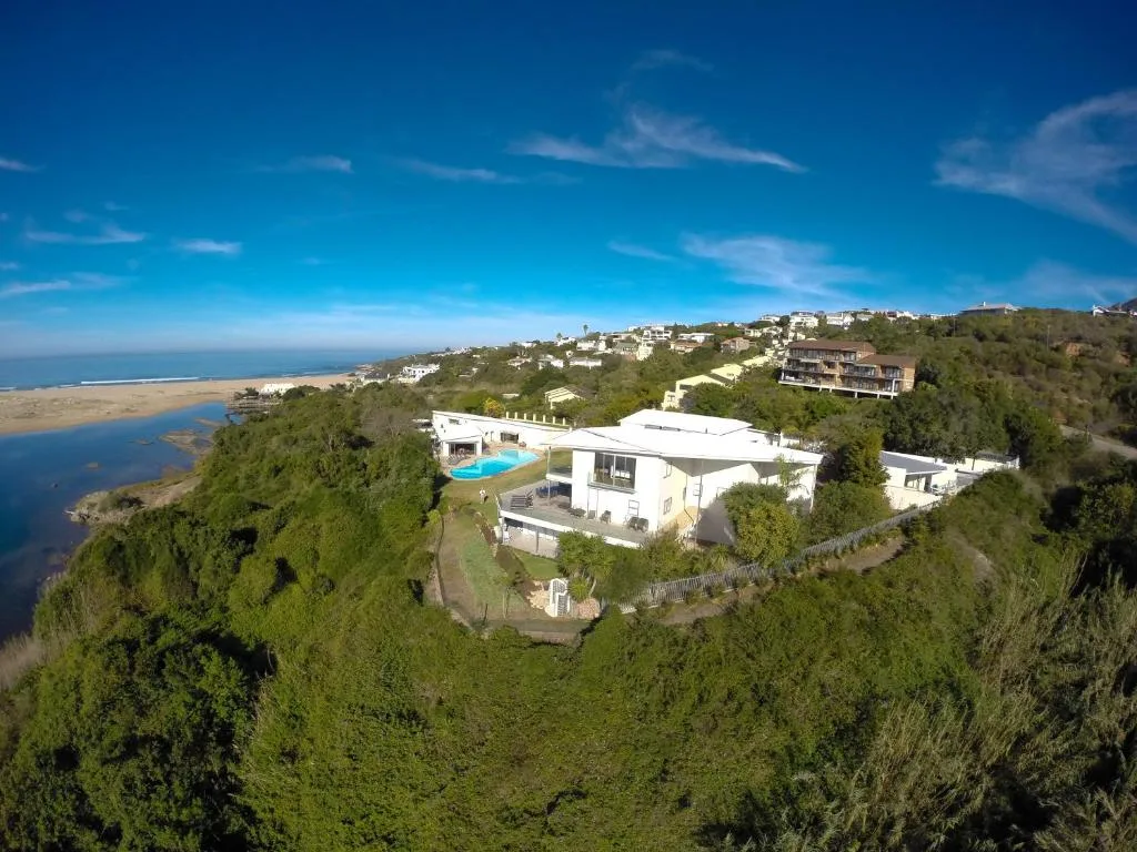 Aerial view of modern white villa on hillside overlooking lagoon and ocean