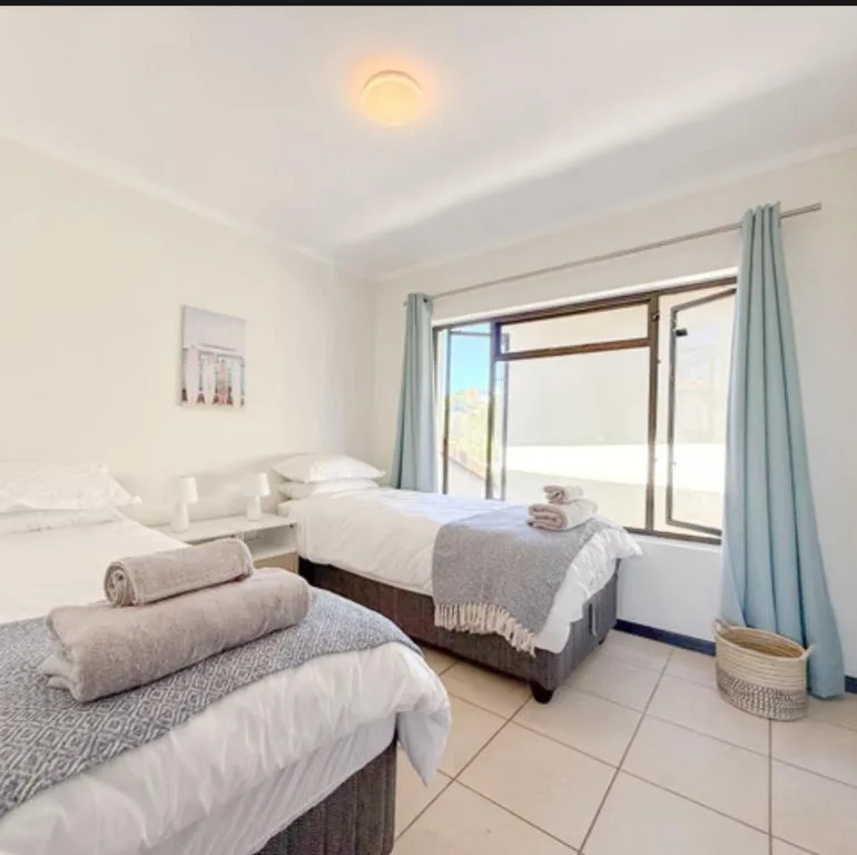 Bright bedroom with two beds and sliding glass doors opening to deck