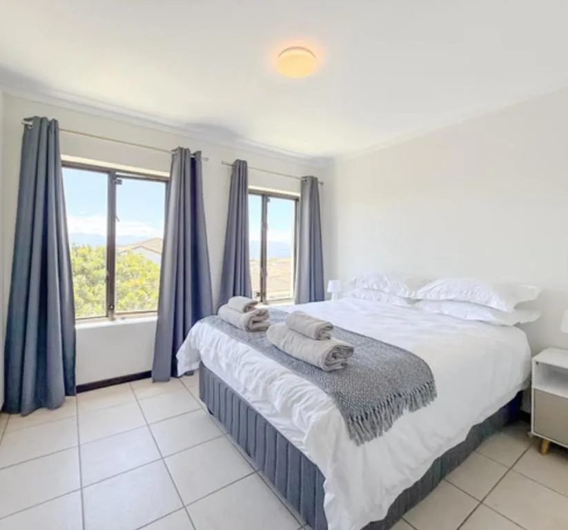 Bright bedroom with white linens, mountain views through large windows