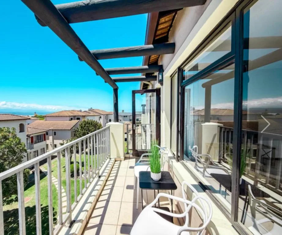 Sunny balcony with pergola, white railings, and mountain views beyond