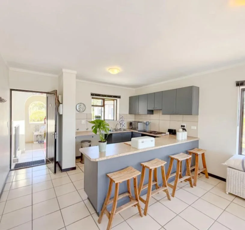 Modern kitchen with gray cabinetry, island counter, and wooden bar stools