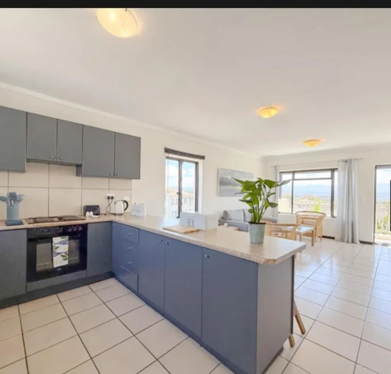 Modern kitchen with gray cabinetry, white tile flooring, and island counter