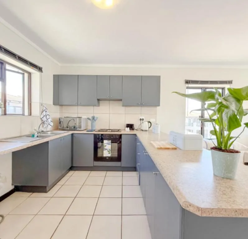 Modern kitchen with gray cabinetry, granite countertop, and stove