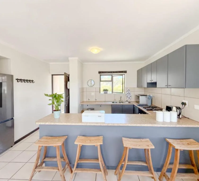 Modern kitchen with gray cabinetry, granite countertop, and wooden bar stools