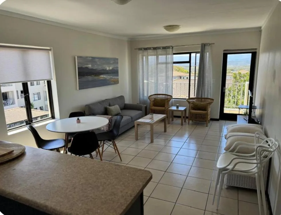 Spacious lounge with gray sofa, armchairs, and garden views through glass doors