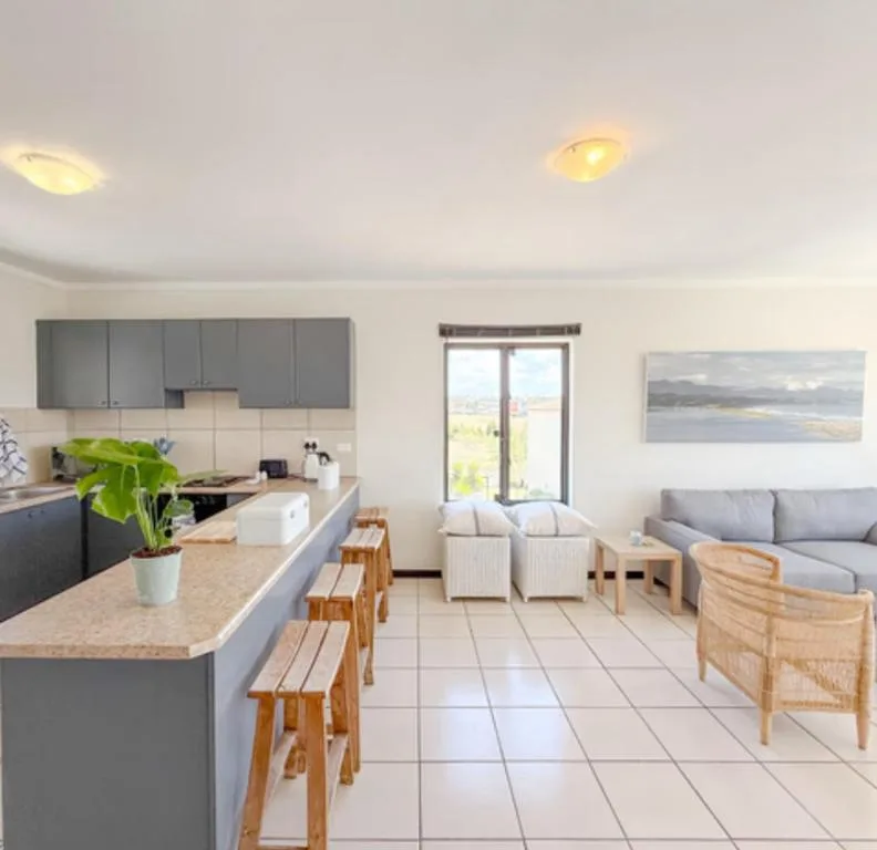 Modern open-plan lounge with gray sofa and natural wood furnishings overlooking garden